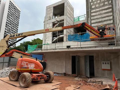 JLG 600AJ articulated boom lift reaching up and over a ledge on a construction site in Johor